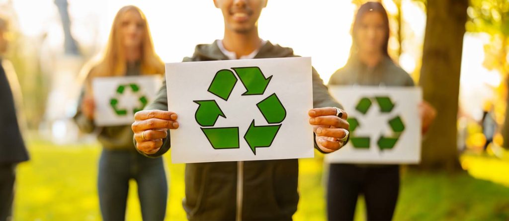 Homem segurando cartaz com símbolo de reciclagem com sua equipe ambiental no parque